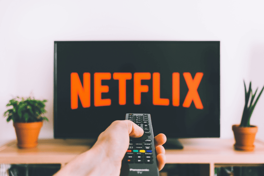 Photo of a person pointing a remote at a television that has the Netflix Logo on it