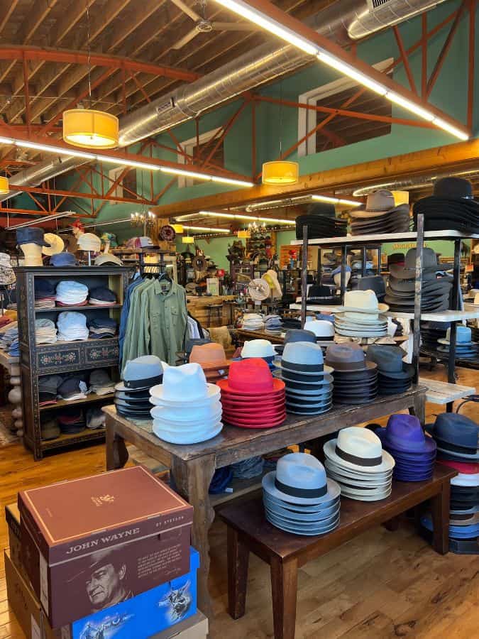 photo of the inside of a hat shop. There are lots of different styles of mens and womens hats, all stacked very neatly