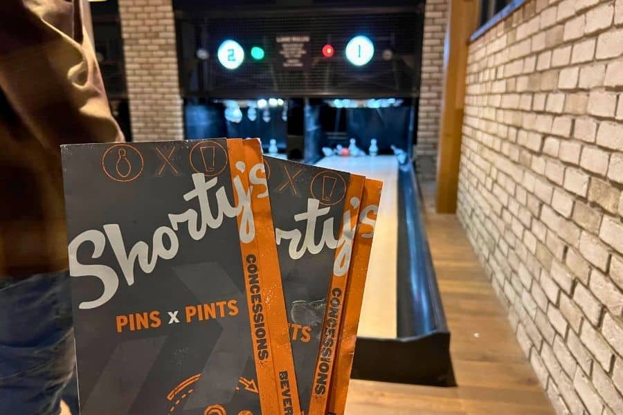 2 Menus held up that read "Shorty's Pins and Pints" in front of a bowling alley