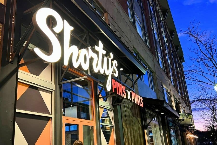 The outside of Shorty's Pins and Pints. it is a neon sign of the name on a street at night